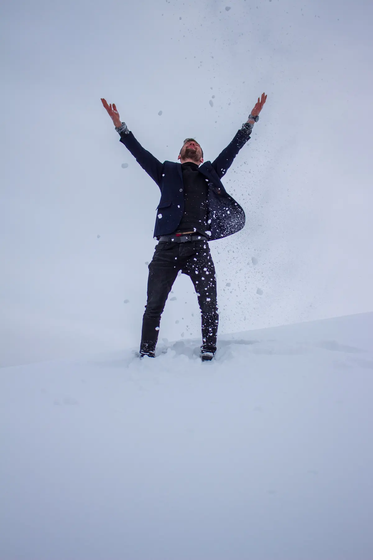 A man tossing snow into the air on an open winter mountain ridge